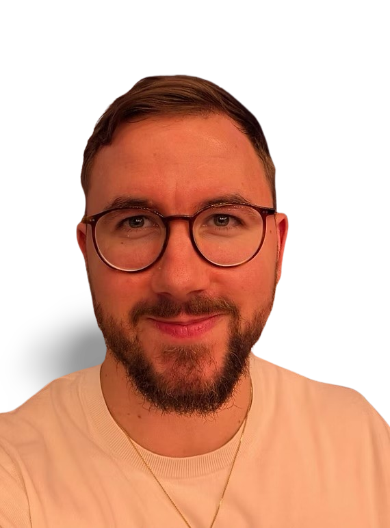 Ein Mann mit Brille und Bart lächelt in die Kamera. Er trägt ein helles Sweatshirt.